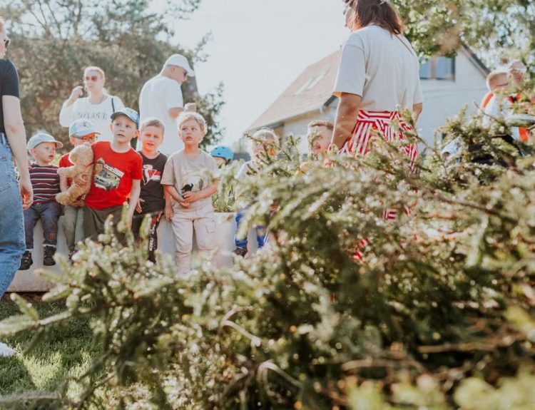 Children and adults participating in an outdoor educational activity surrounded by nature.